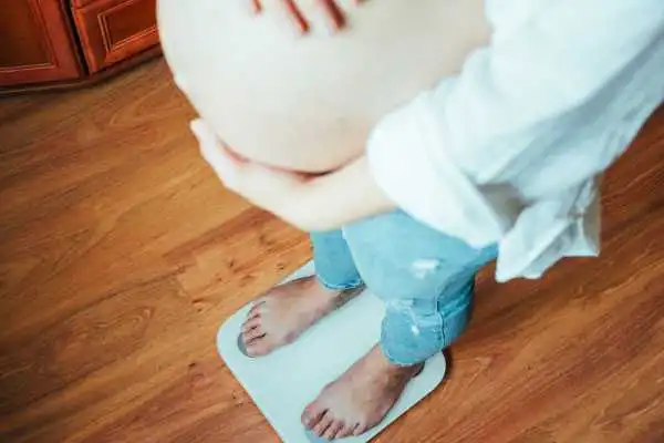 Image of woman weighing herself and experiencing weight gain through pregnancy Felixstowe